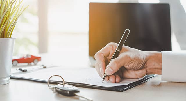 a person signing papers on a desk