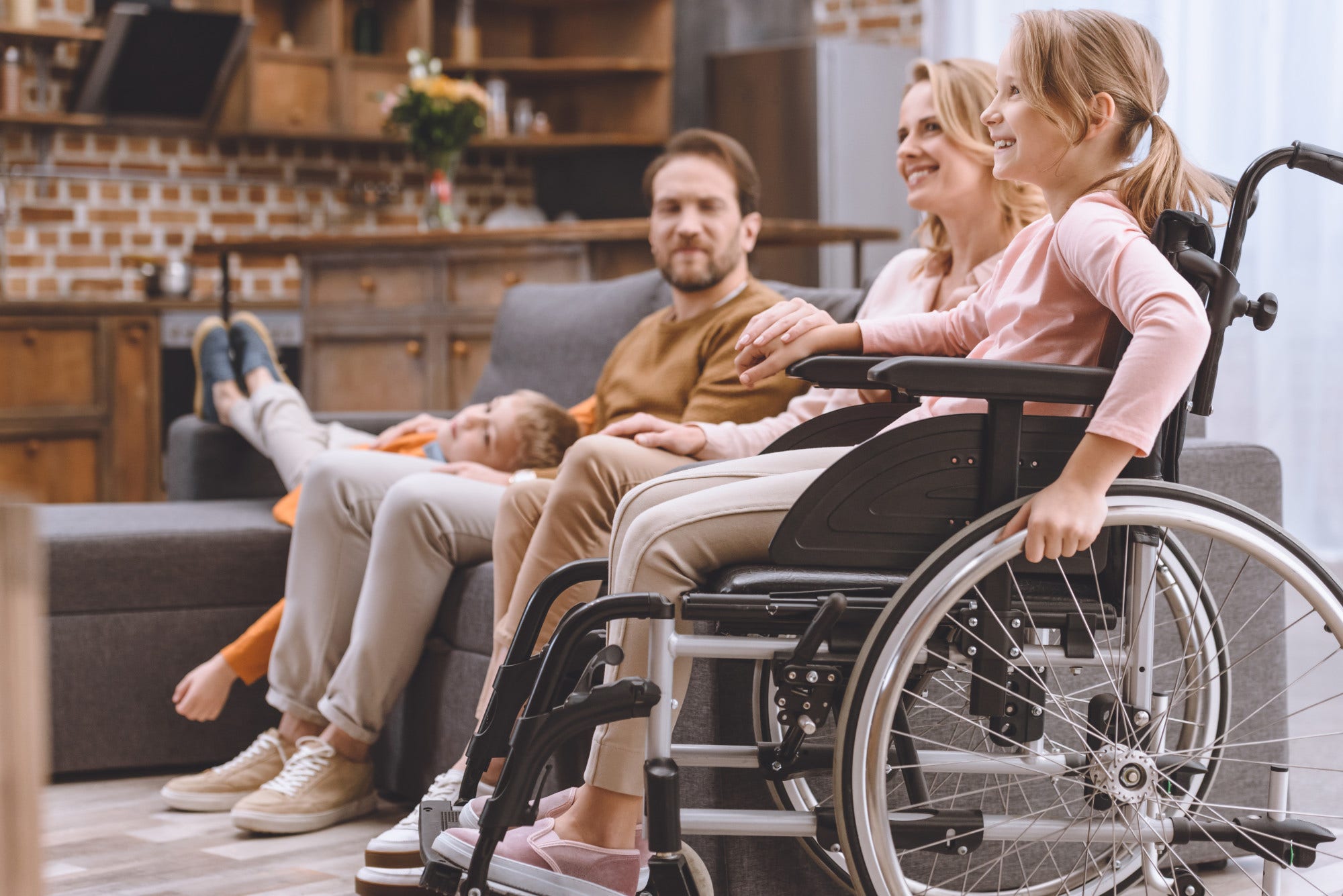 happy family with disabled little daughter in wheelchair spending time together at home