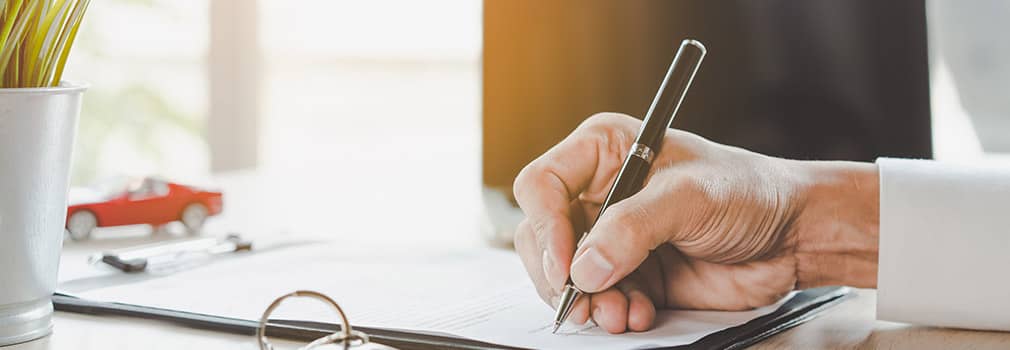 a person signing papers on a desk