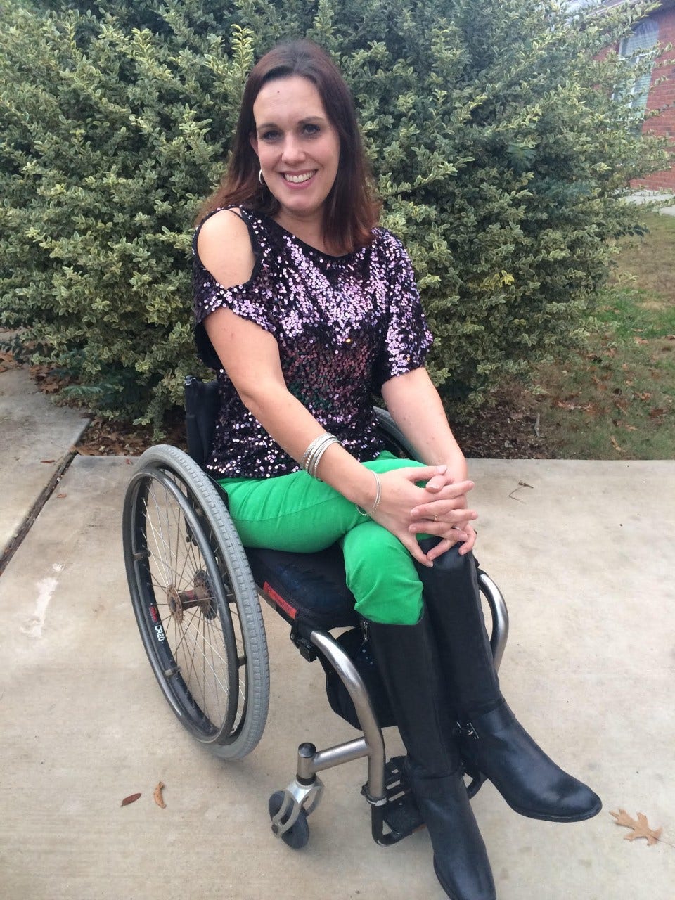 Priscilla Hedlin is wearing a sparkly purple shirt, green pants and black leather boots