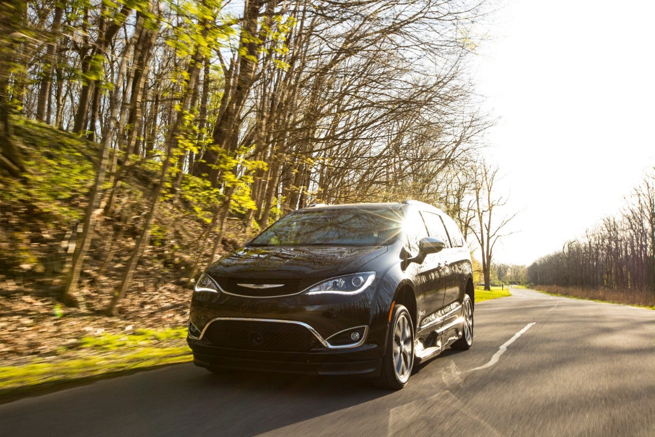 BraunAbility Chrysler Pacifica driving on a road while the sun shines overhead